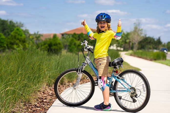Little kid boy ride a bike in the park. Kid cycling on bicycle. Happy smiling child in helmet riding a bike. Boy start to ride a bicycle. Sporty kid bike riding on bikeway. Kids bike.