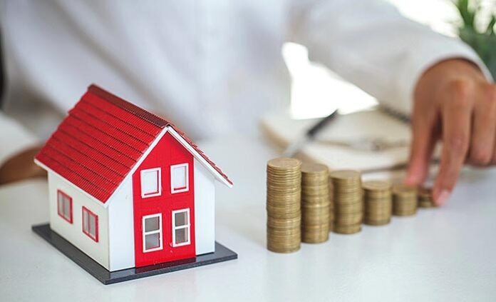 Hand putting money coin stack with model house; Property investm