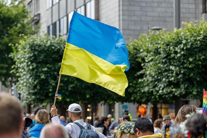 man is holding Ukraine flag during gay parade in city street