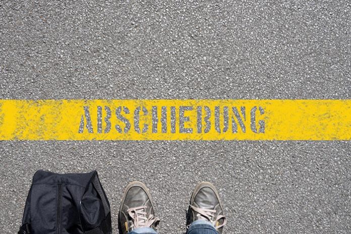 Ein Mann mit Koffer steht kurz vor der Abschiebung