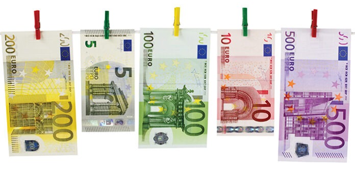 Geld-Euroscheine hängen an Wäscheklammern vor weißem Hintergr