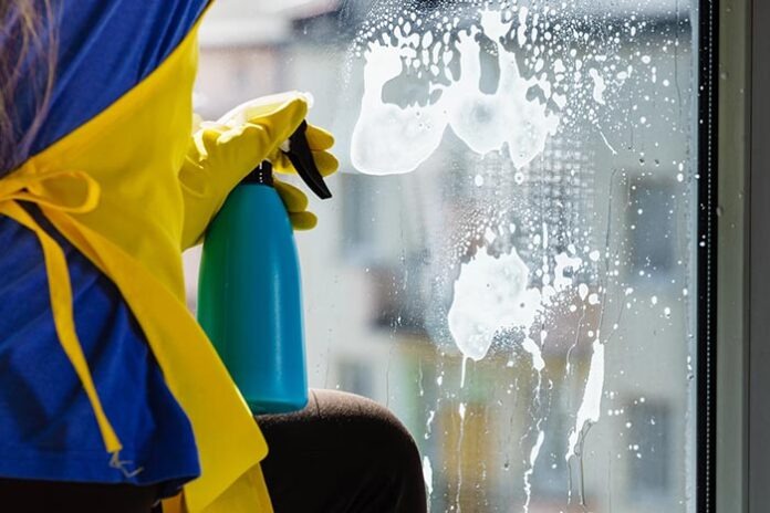 Person spraying window cleaning detergent