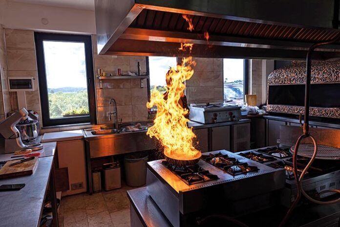 Chef creates flame in pan. Chef cooking with flame in a frying p