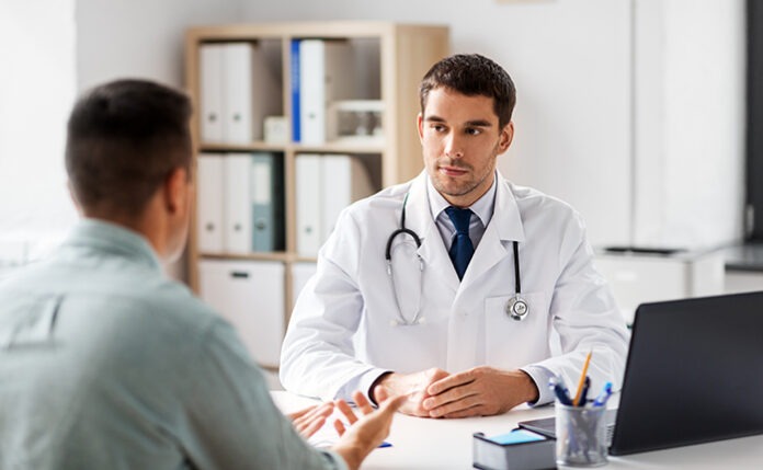 doctor with laptop and male patient at hospital