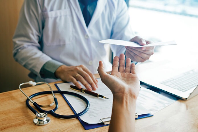 Male doctor handing a prescription to the patient.