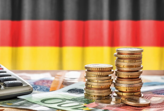 Euro banknotes and coins in front of the national flag of Germany