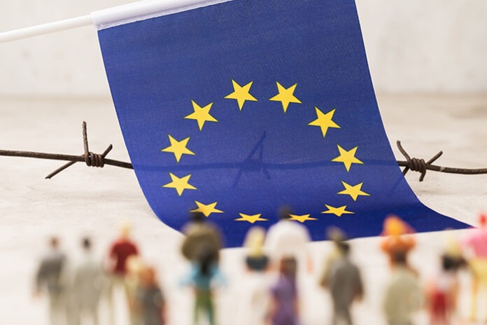 EU flag, barbed wire and plastic toy men out of focus, concept o