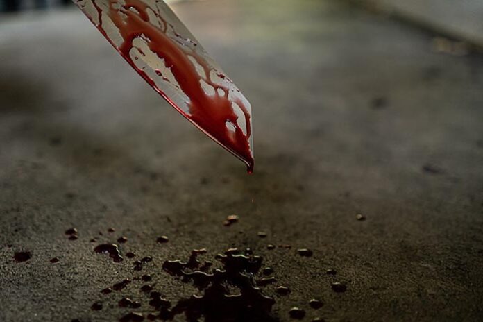 Close-up of the knife with blood stains and dripping on the floo