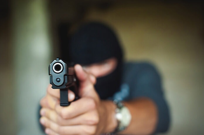 Athletic man in a balaclava, holds a pistol in his hand, is thre