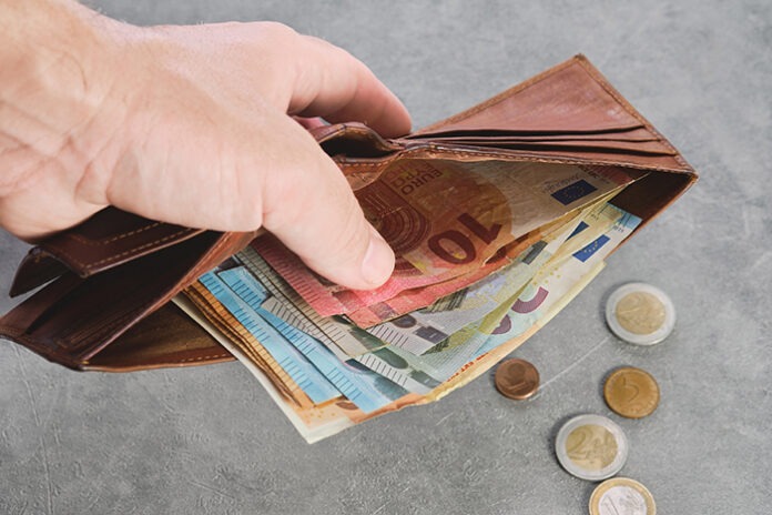 Senior man holds a wallet with euro banknotes in his hand, euro banknotes in the wallet. Wallet with money in a man's hand, background idea of paying taxes, buying or paying for services