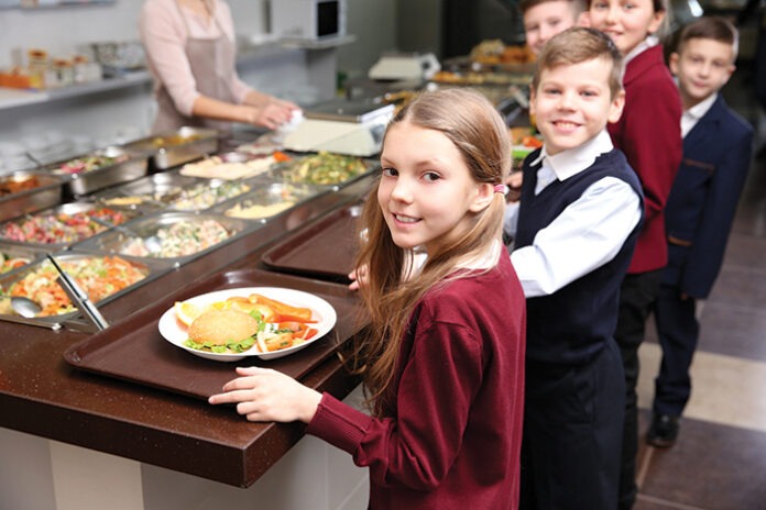 Beautiful little girl receiving food in school cafeteria