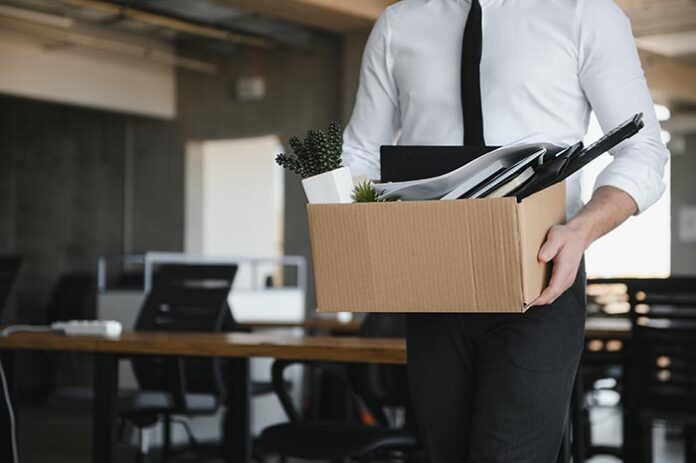 Sad Fired. Let Go Office Worker Packs His Belongings into Cardboard Box and Leaves Office. Workforce Reduction, Downsizing, Reorganization, Restructuring, Outsourcing. Mass Unemployment Market Crisis