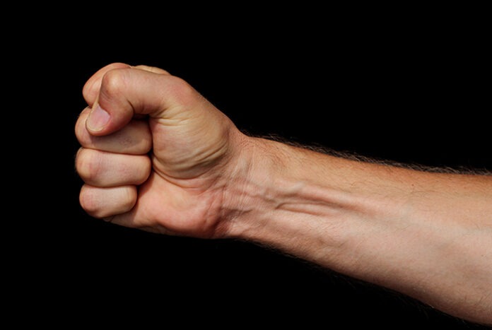Male fist on a black background. Symbol of resistance and willpower.