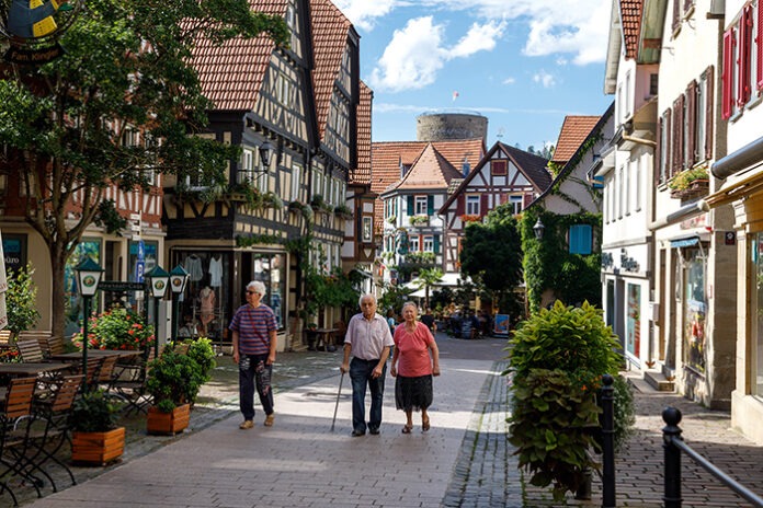 Older tourists stroll through the streets of a small old German city. Image of active old age, a taste for life, vitality in old age. Besigheim, Germany - August 10, 2019