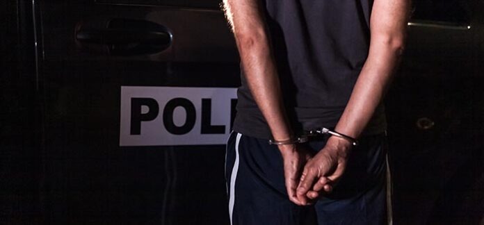 criminal with handcuffs in front of a police car