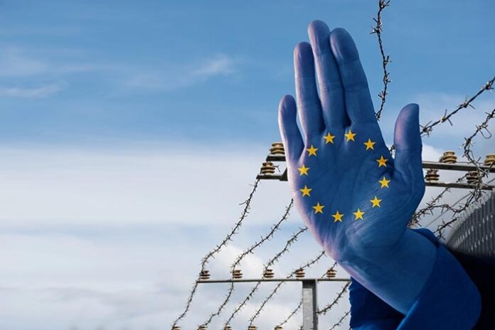 Hand with European flag stops immigration of refugees, blurred b