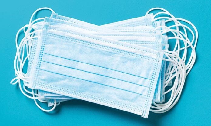 Top view of pile of protective medical masks on blue background. Respiratory syndrome. Protect your health concept