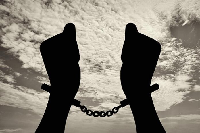 Silhouette of human hands in handcuffs