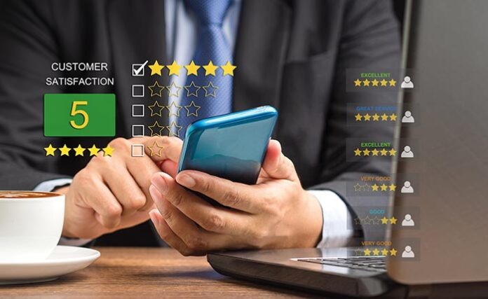 A businessman in a suit using a smartphone giving the five-star